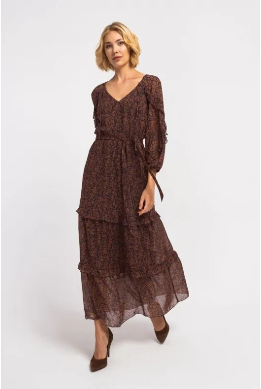 Długa, kobieca sukienka maxi z wiązaniem w talii, podkreślającym figurę. Dekolt w serek, długie rękawy, rozkloszowany krój.
