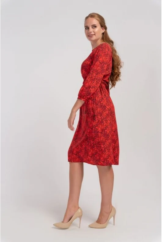 Czerwona elegancka sukienka kobieca o średniej długości, z nadrukiem, z wiskozy. Luźny krój, podkreślona talia, dekolt w łódkę.