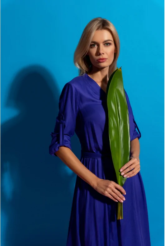 Niebieska sukienka midi z lśniącej wiskozy, wiązaniem w talii i rozkloszowaną spódnicą.  Idealna na specjalne okazje i do biura.