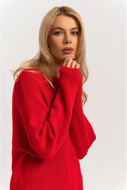 Czerwony szeroki sweter nietoperz o grubym splocie z bawełny z dekoltem w łódkę. Stylizacja na wiosnę.