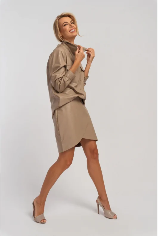 Kopertowa spódnica mini z ołówkowym fasonem w kolorze beżowym wykonana z eko skóry. Nowoczesna stylizacja do biura.