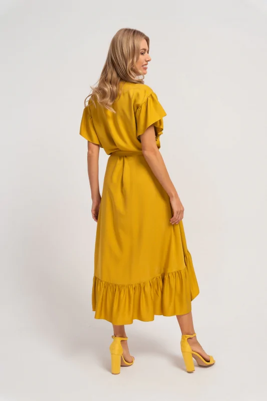 Długa żółta sukienka z wiązaną talią, podkreślająca kobiecą figurę. Elegancka i luźna forma.